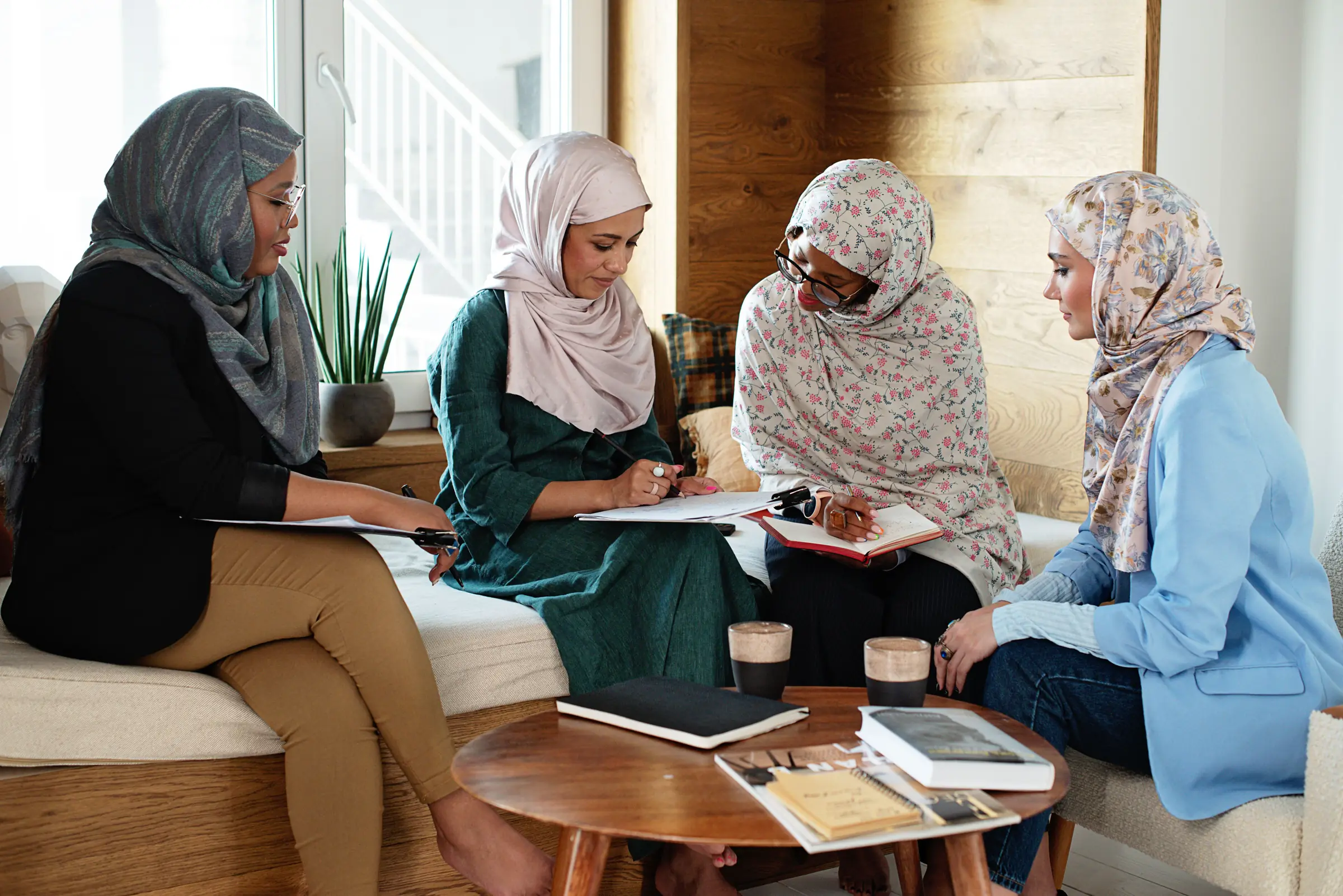 A small group of women discussing notes around a low café table
