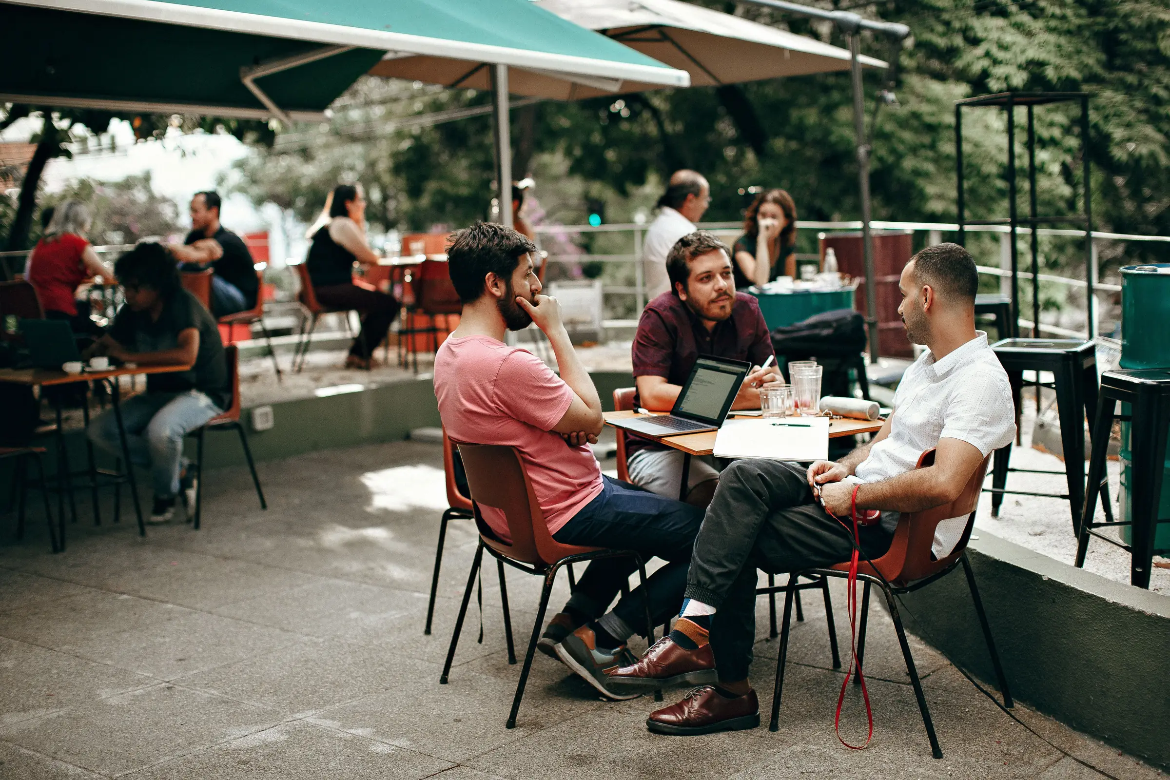 Three professionals talking at an outdoor café table