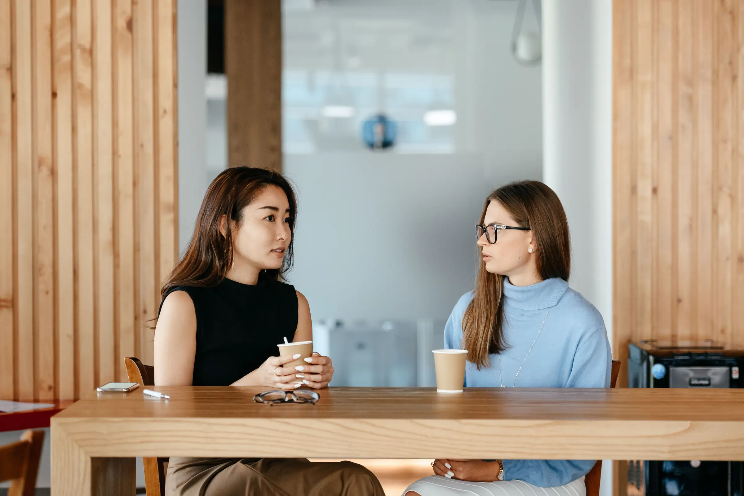 Two women in conversation at a long café table